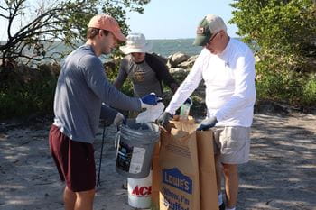 Kurt Allebach (right) opens a paper waste bag to be filled with trash.